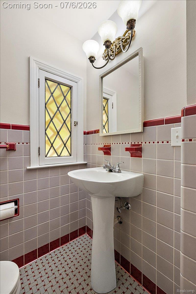1051 Devonshire Road Grosse Pointe, MI 48230 - Photo 28 of 98 Pedestal sink with chrome fixtures, set against gray wall tiling with a red accent border