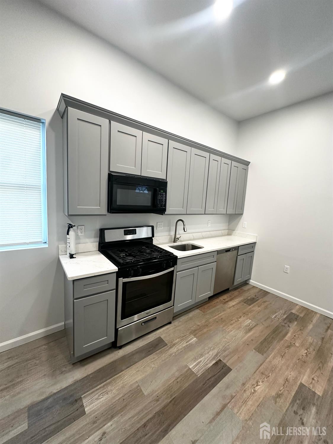 55 Cutters Dock Road, Unit B Woodbridge, NJ 07095 - Photo 4 of 13 a kitchen with stainless steel appliances a stove a microwave a sink and a hard wood floors