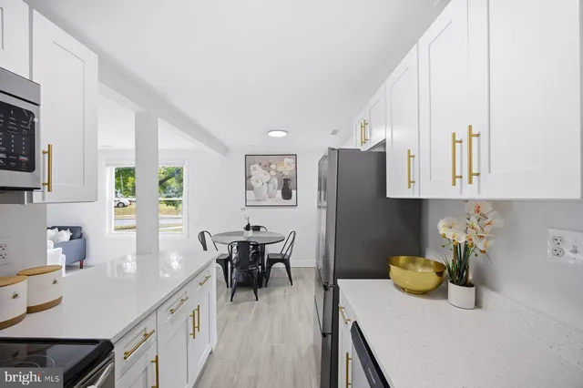 a kitchen with stainless steel appliances granite countertop a refrigerator a sink dishwasher a dining table and chairs with wooden floor