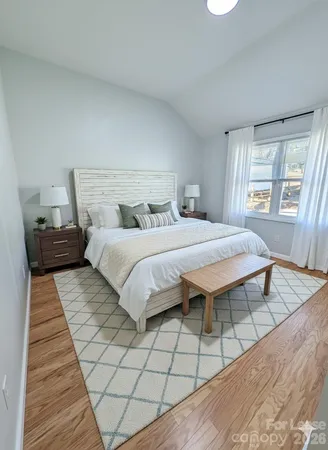 a bedroom with a bed and a night stand with wooden floor