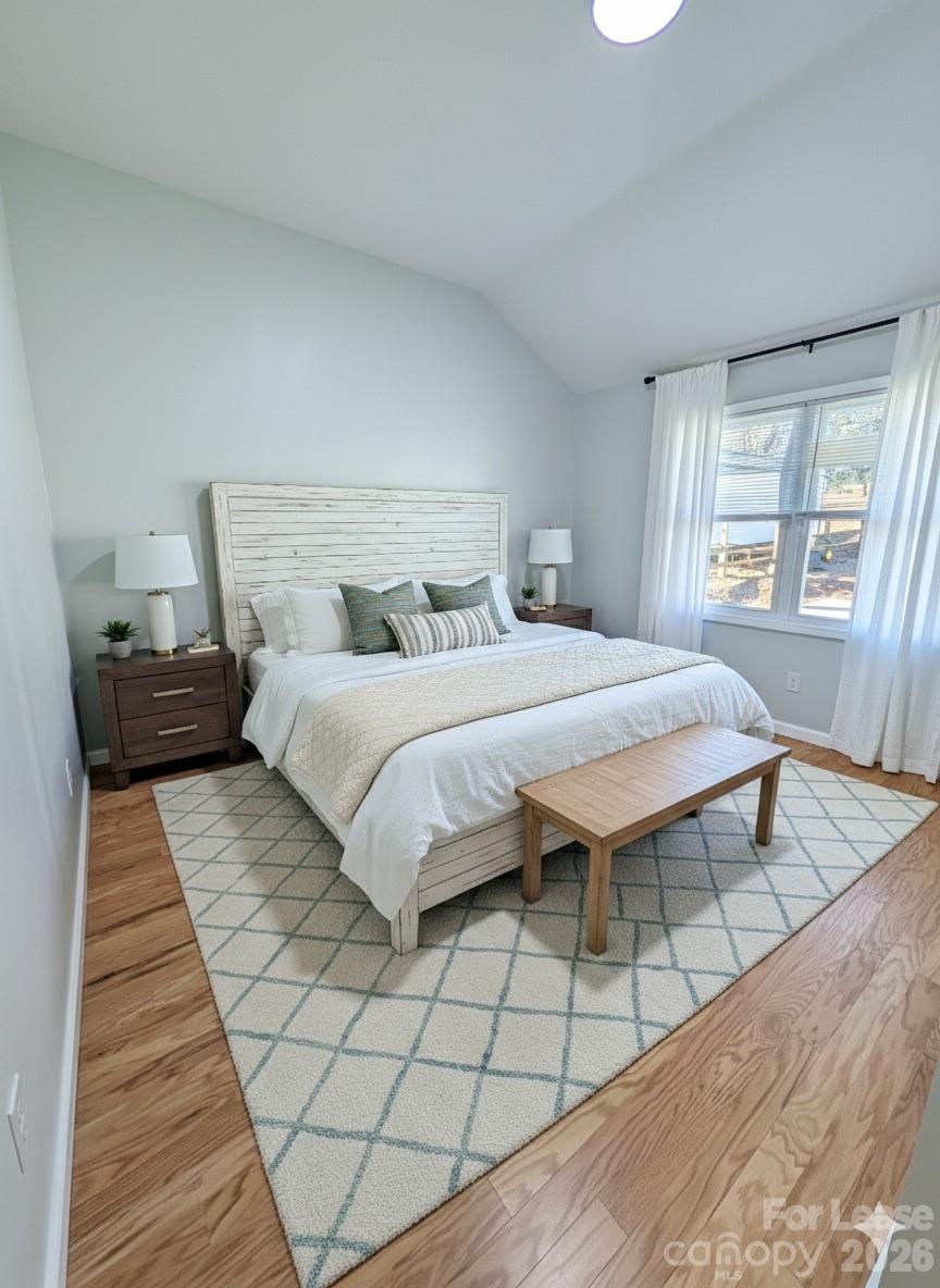 3211 Winding Trail, Unit 2 Matthews, NC 28105 - Photo 3 of 10 a bedroom with a bed and a night stand with wooden floor