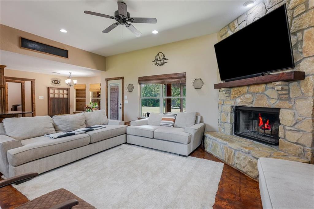 181 Savannah Drive Weatherford, TX 76087 - Photo 4 of 36 a living room with furniture a flat screen tv and a fireplace