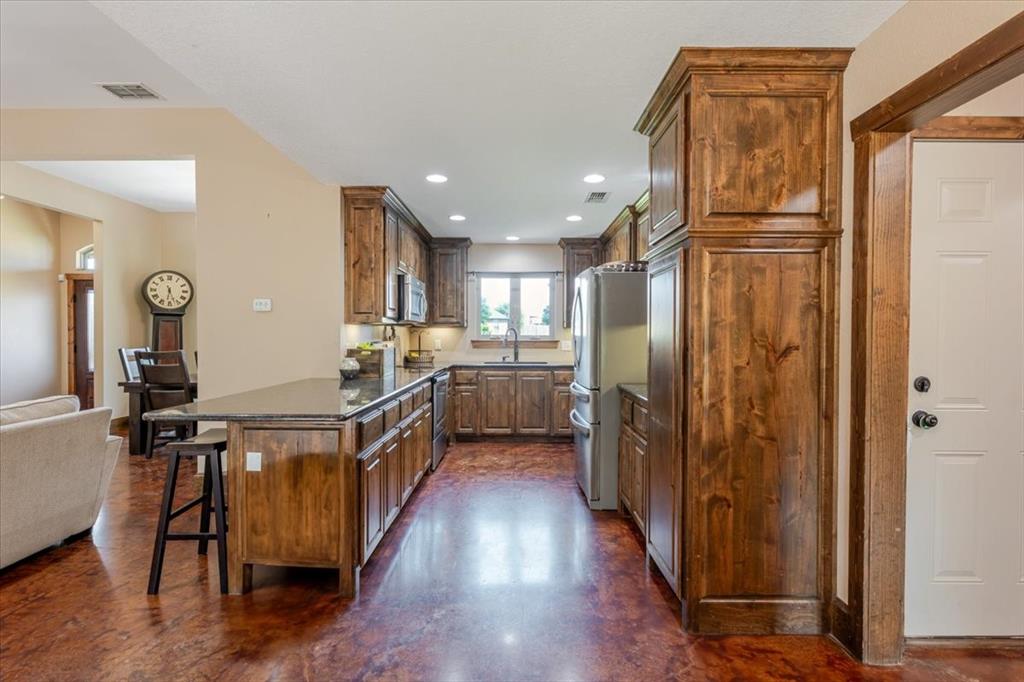 181 Savannah Drive Weatherford, TX 76087 - Photo 7 of 36 a kitchen with stainless steel appliances granite countertop a refrigerator a sink dishwasher a stove and a dining table with wooden floor