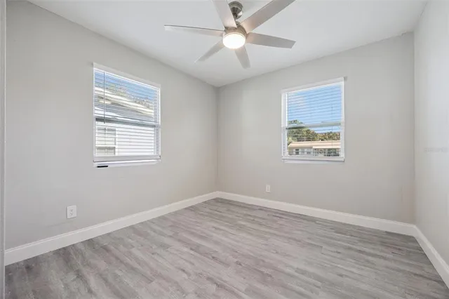 a view of empty room with wooden floor and fan