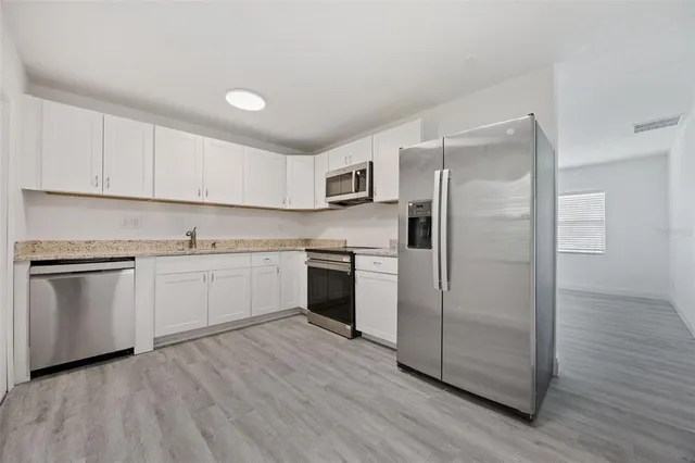 a kitchen with a refrigerator sink and cabinets
