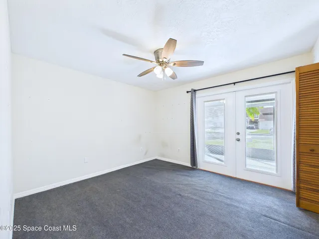 an empty room with windows and fan