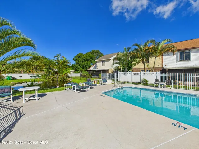 a view of a swimming pool with a lawn chairs under an umbrella