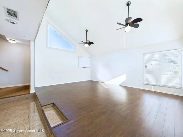 an empty room with wooden floor cabinet and windows