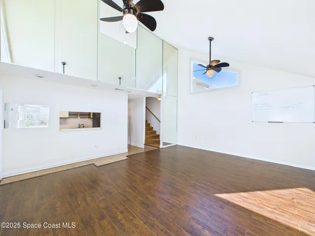 a view of an empty room with a window and wooden floor