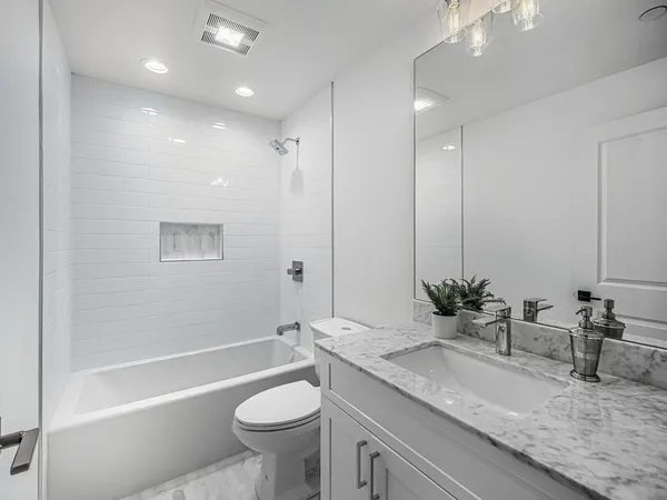 a bathroom with a granite countertop sink a toilet a mirror and bathtub