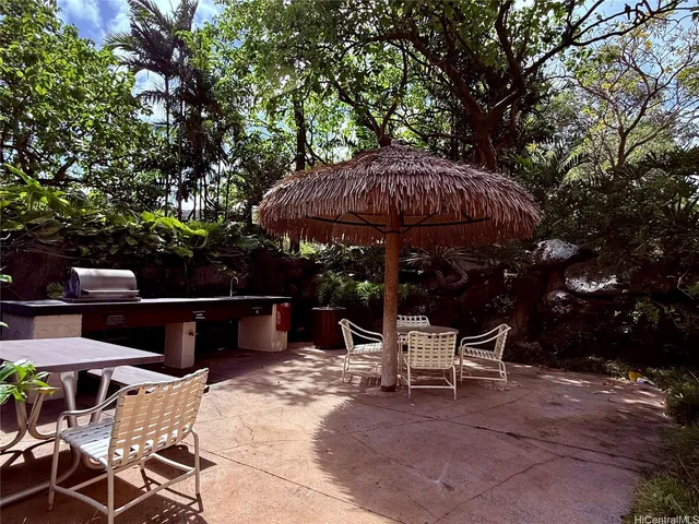 a view of patio with table and chairs under an umbrella