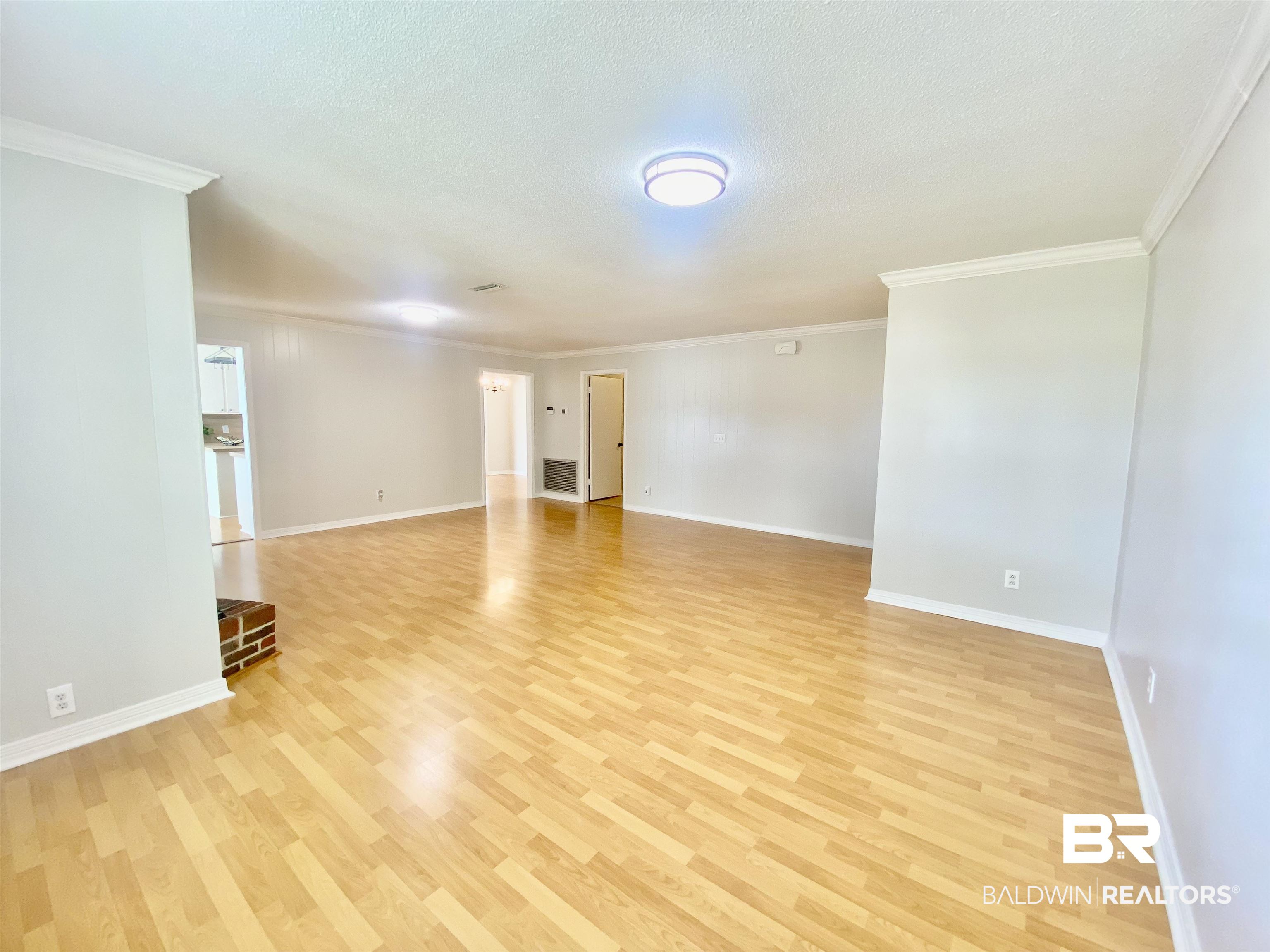 265 Azalea Drive Monroeville, AL 36460 - Photo 6 of 39 Empty room featuring light hardwood / wood-style floors, a textured ceiling, and ornamental molding