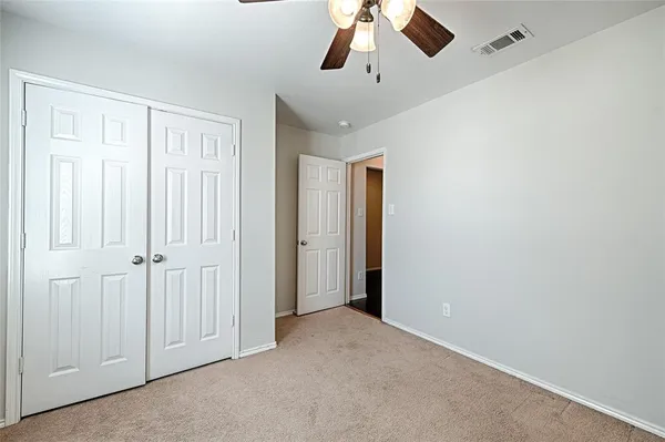 a view of an empty room and chandelier fan
