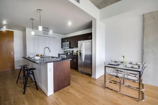 a kitchen with kitchen island a counter top space a sink stainless steel appliances and cabinets