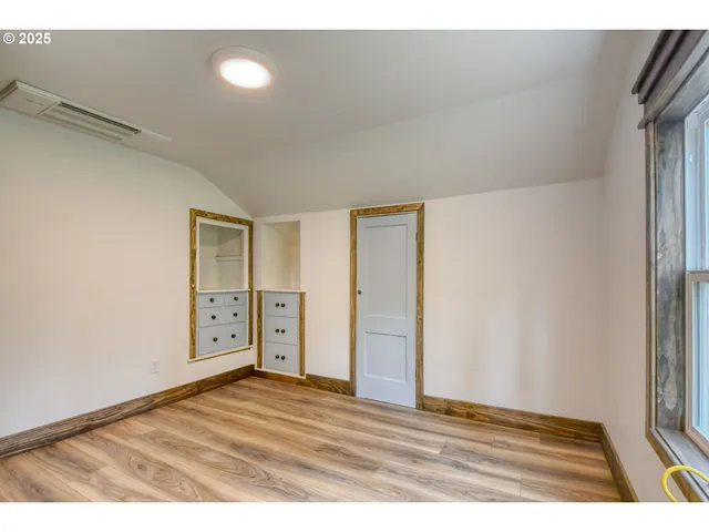 a view of an empty room with closet and wooden floor