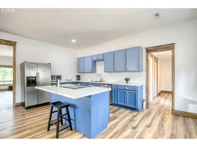 a kitchen with a refrigerator a sink dishwasher and wooden cabinets with wooden floor