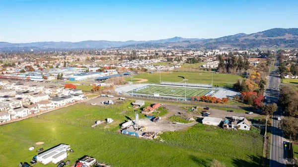 an aerial view of a city with lots of residential buildings ocean and mountain view in back