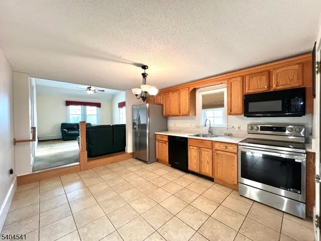 a large kitchen with stainless steel appliances granite countertop a stove top oven a sink dishwasher a dining table and chairs with wooden floor