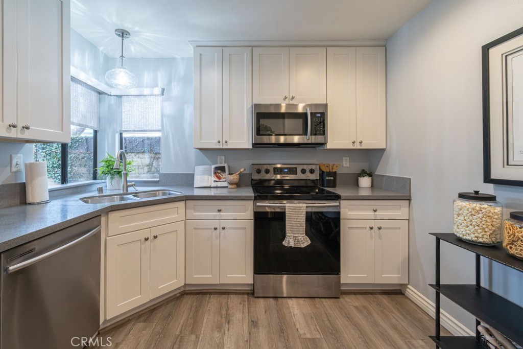 5002 East Atherton Street Long Beach, CA 90815 - Photo 17 of 52 a kitchen with a white cabinets a sink dishwasher and a stove with wooden floor