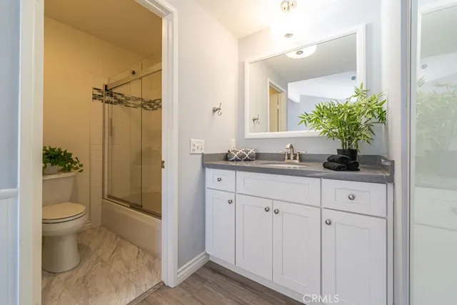a bathroom with a granite countertop sink a toilet a mirror and shower