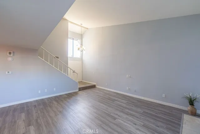 a view of an empty room with wooden floor and stairs