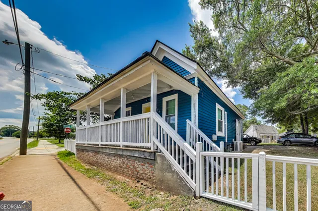 a view of house with a small yard and wooden fence