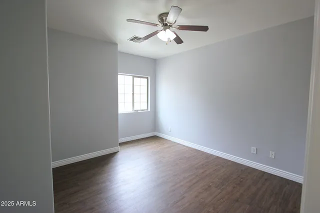 a view of an empty room with a window and wooden floor