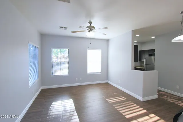 a view of empty room with wooden floor and fan