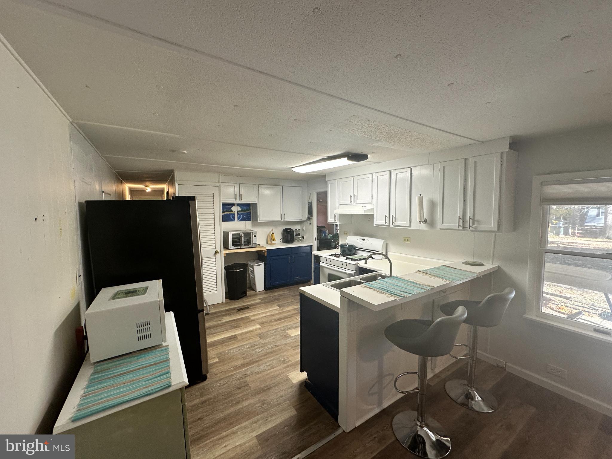 34481 Broad Water Road, Unit 643 Long Neck, DE 19966 - Photo 8 of 21 a kitchen with stainless steel appliances kitchen island granite countertop a table chairs and a refrigerator