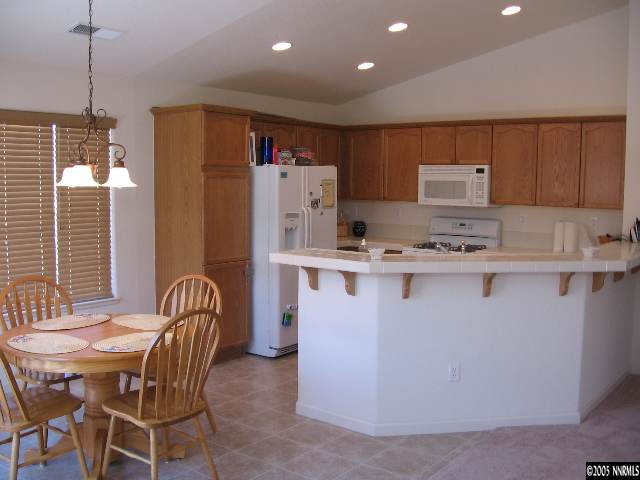 1753 Camaraderie Way Reno, NV 89521 - Photo 4 of 8 a kitchen with stainless steel appliances kitchen island granite countertop a table chairs and a refrigerator