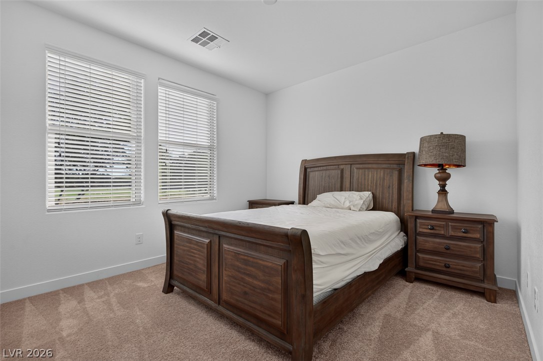 1100 East Sunset Road Henderson, NV 89011 - Photo 26 of 58 Well-lit sleeping quarters with a richly stained wood bed frame and carpeted floor, offering comfort and light.