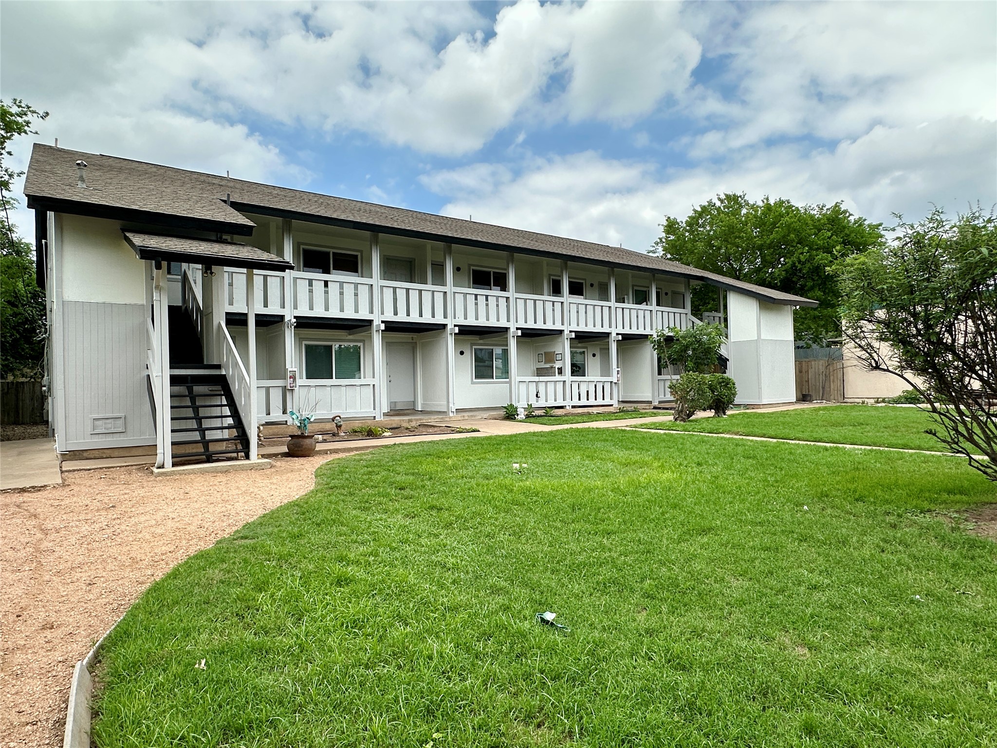 10810 Newmont Road, Unit 7 Austin, TX 78758 - Photo 5 of 13 The property features a two-story building with white exterior siding and dark accents, surrounded by a well-maintained green lawn