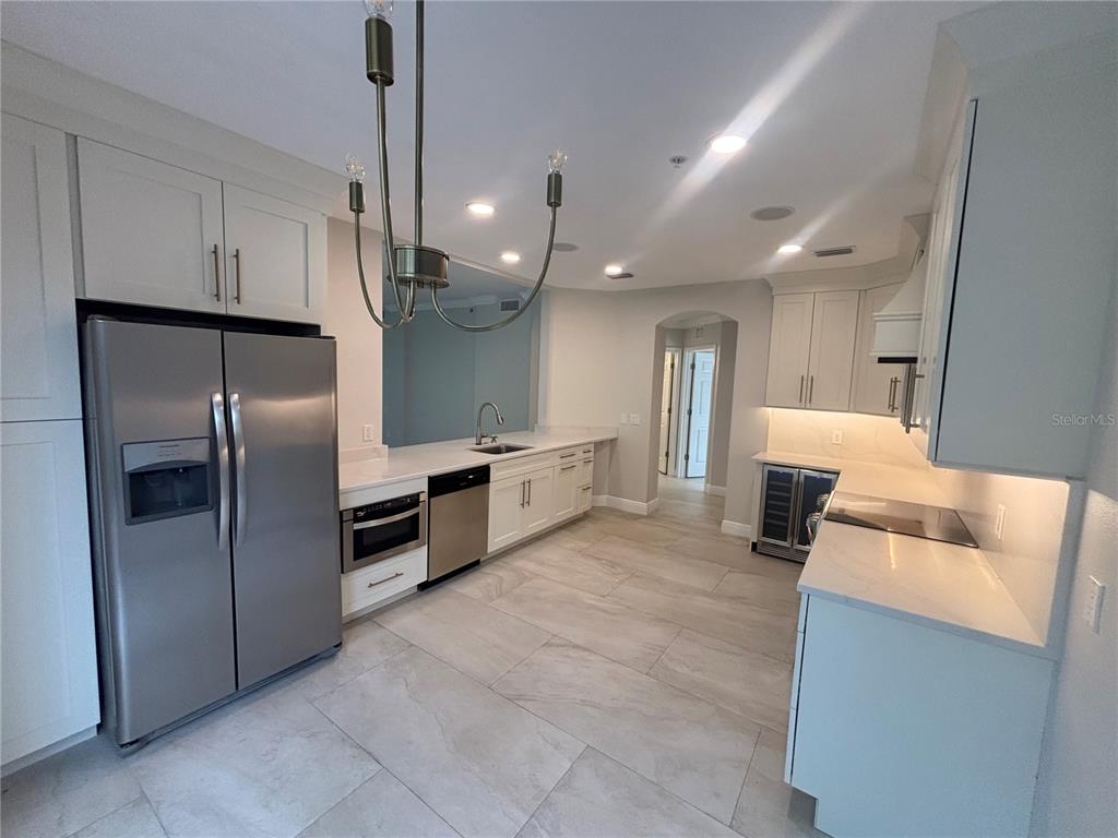 6536 Moorings Point Circle, Unit 101 Lakewood Ranch, FL 34202 - Photo 6 of 34 a large kitchen with stainless steel appliances kitchen island granite countertop a refrigerator and a sink