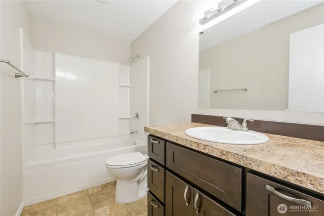 a bathroom with a granite countertop sink a toilet and shower