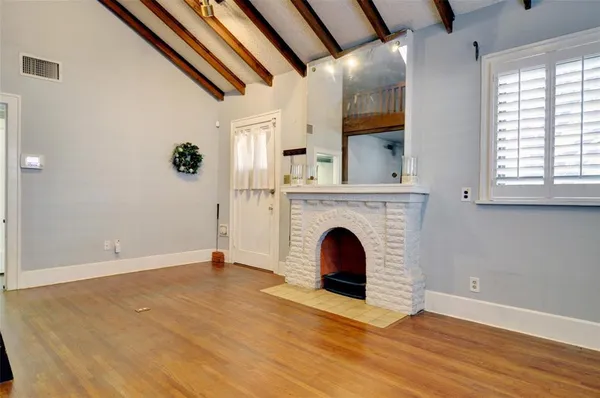 a view of an empty room with wooden floor and a fireplace