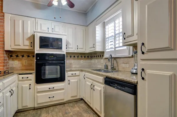 a kitchen with stainless steel appliances granite countertop white cabinets a sink a stove a window and dishwasher