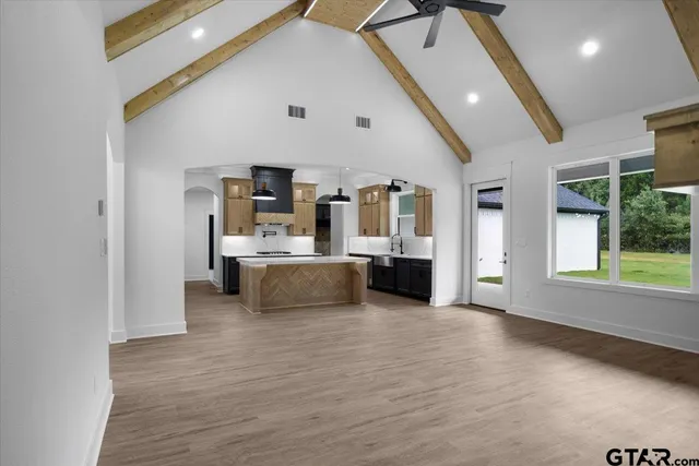 a large white kitchen with stainless steel appliances kitchen island a large counter top and a fireplace