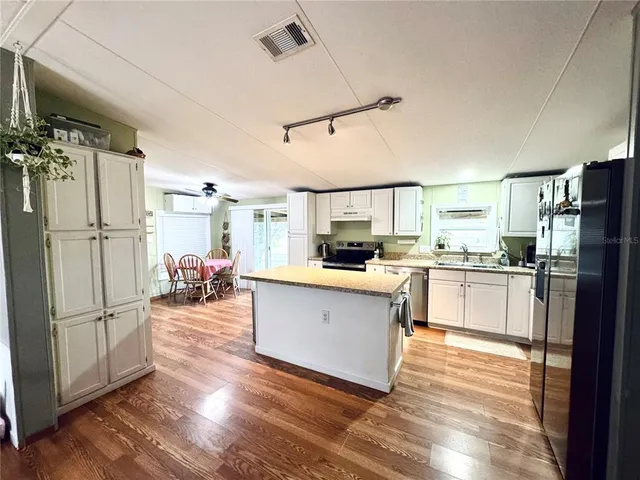 a kitchen with granite countertop wooden floors and white stainless steel appliances