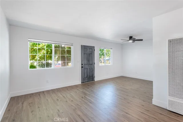 an empty room with wooden floor and windows