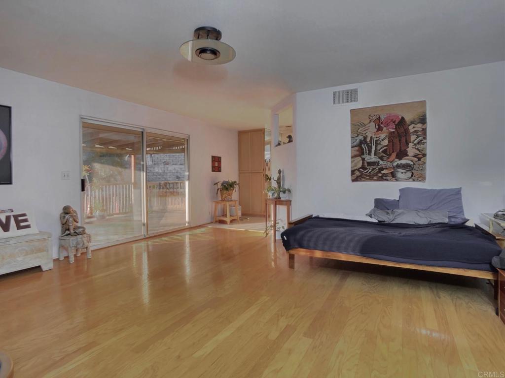 8242 Sunset Road Lakeside, CA 92040 - Photo 21 of 48 a spacious bedroom with a bed and wooden floor