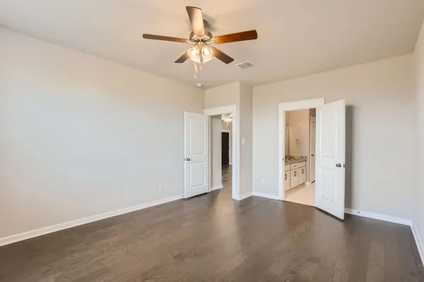 an empty room with wooden floor ceiling fan and windows