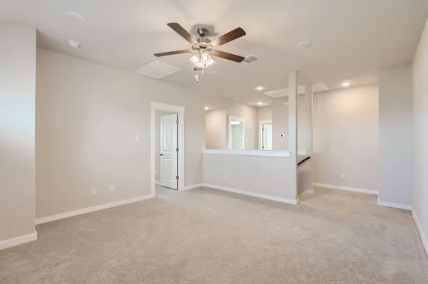 an empty room with ceiling fan and windows