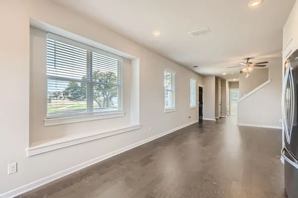 a view of an empty room with a window and wooden floor
