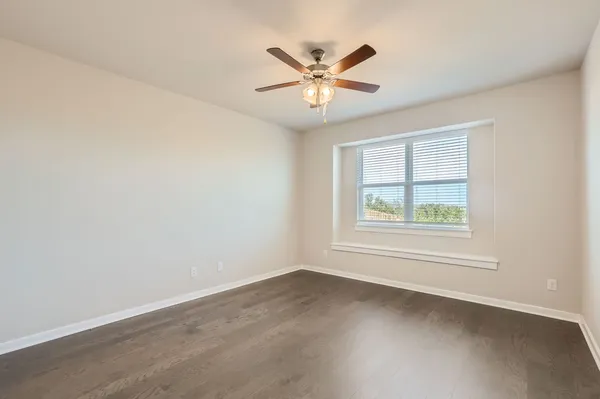 an empty room with window and ceiling fan