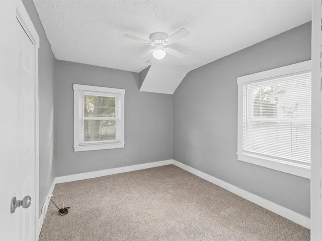 an empty room with a window and ceiling fan