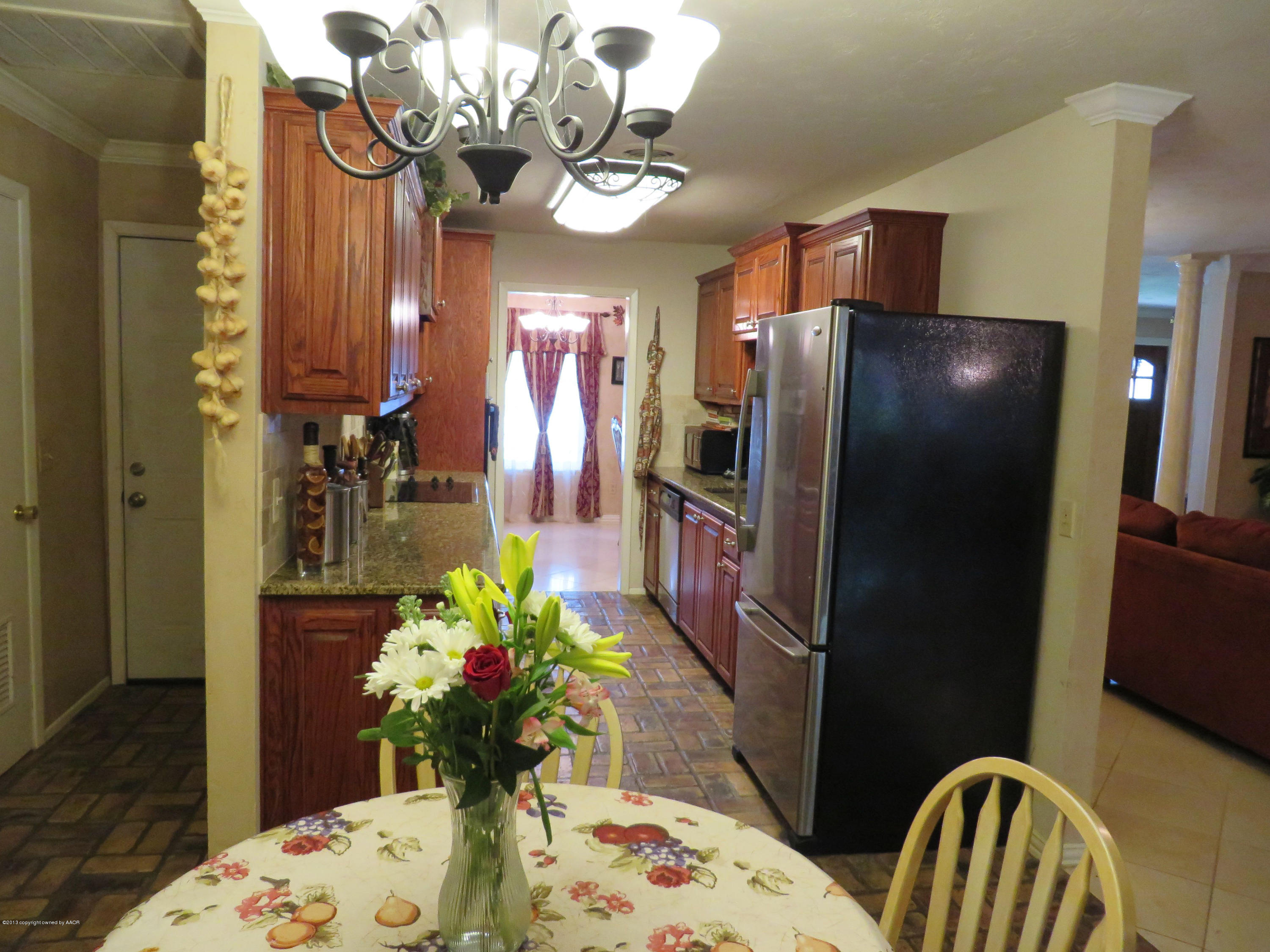 6713 Jameson Road Amarillo, TX 79106 - Photo 7 of 23 a dining room with stainless steel appliances furniture a chandelier and a wooden floor