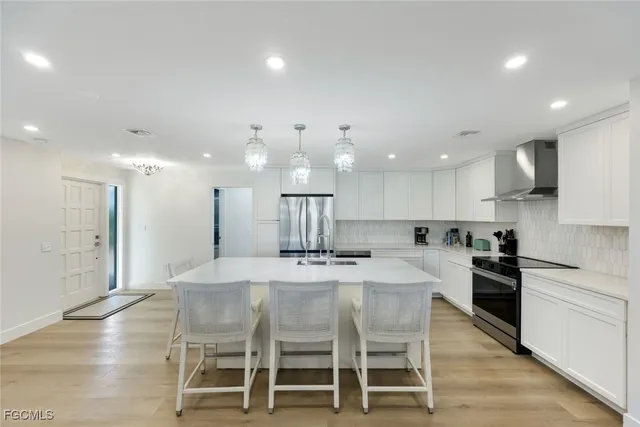 a kitchen with stainless steel appliances kitchen island granite countertop a table chairs sink and cabinets