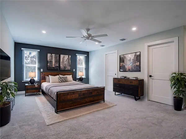 a spacious bedroom with a bed a couch and paintings on the wall