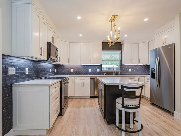 a kitchen with kitchen island granite countertop a sink cabinets and wooden floor