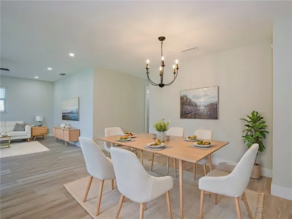 a view of a dining room with furniture a chandelier and wooden floor